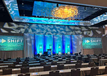 Clean corporate stage set with dual screens